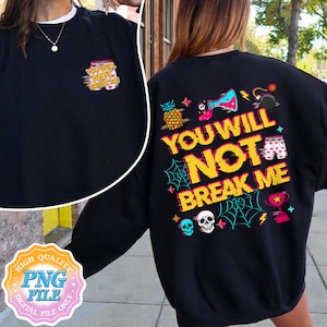 May include: Black sweatshirt with the text "YOU WILL NOT BREAK ME" in yellow and red. The design includes a pineapple, beaker, bomb, and other graphics. A smaller version of the text is on the front.