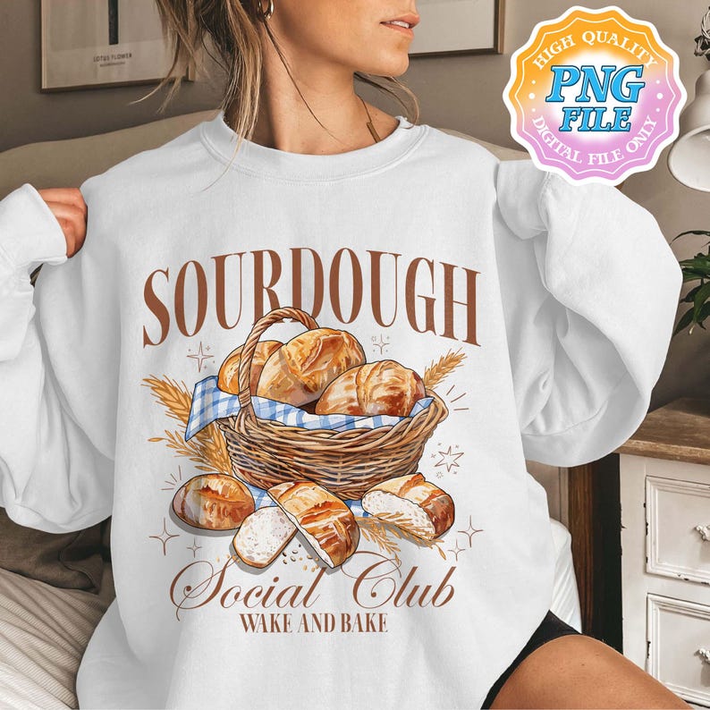 May include: White sweatshirt with a brown graphic of a basket of sourdough bread and the text "Sourdough Social Club Wake and Bake".