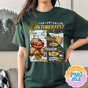 May include: Dark green t-shirt featuring an Oktoberfest design. The graphic includes wooden barrels, beer steins, pretzels, and directional signs for Biergarten, Music, Food, and Dancing. The word "Oktoberfest" is written in gold script.