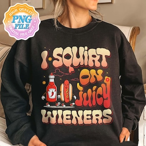 Op de afbeelding: Zwart sweatshirt met de tekst "I Squirt on Juicy Wieners" in een retro lettertype. De afbeelding bevat een cartoon ketchupfles en een hotdog, beide met armen en benen. Het ontwerp heeft een vintage, speelse stijl.
