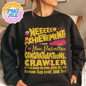 May include: Dark gray sweatshirt with the text "NEEEEEW ACHIEVEMENT! I You, Valentine CONGRATULATIONS, CRAWLER". The design includes a pink donut, hearts, and pixelated graphics. The text also reads "YOU CHOSE ROMANCE OVER OPTIMAL SURVIVAL STATS, BOLD REWARD: THIS SHIRT, LOVE YOU."