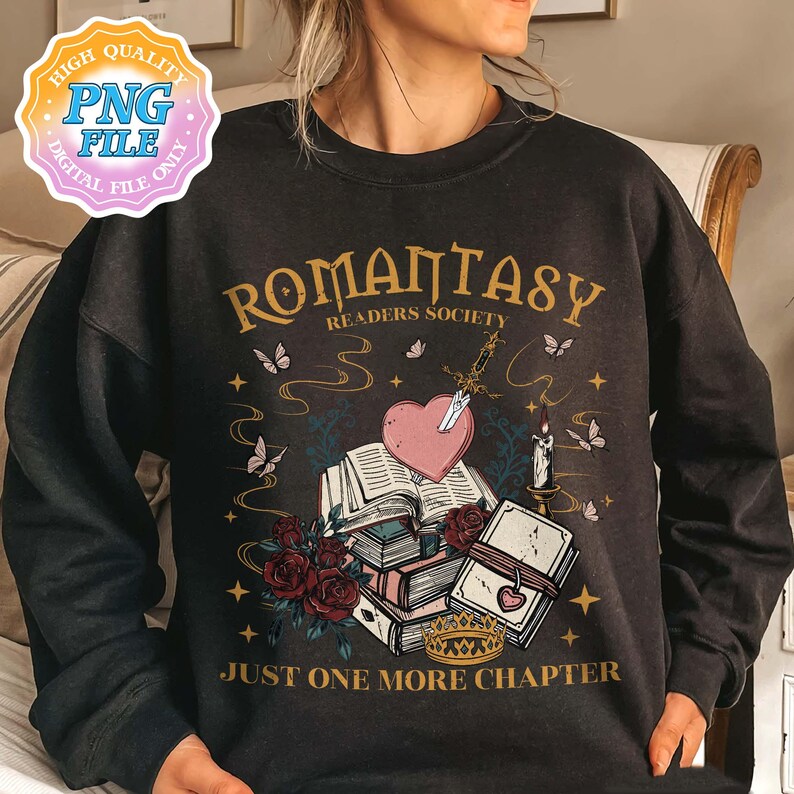 May include: Black sweatshirt featuring a graphic design of a stack of books, a heart, a sword, and a candle. The text "Romantasy Readers Society" and "Just One More Chapter" is printed on the sweatshirt.