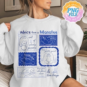 May include: White sweatshirt with a blue graphic design featuring manatees and the text "Advice from a Manatee." The design includes phrases like "eat plenty of greens" and "just keep floating."