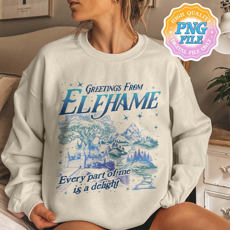 K&ouml;nnte beinhalten: Ein wei&szlig;er Pullover mit einem blauen und wei&szlig;en grafischen Druck eines Schlosses und B&auml;umen. Der Text "Greetings from Elfhame" und "Every part of me is a delight" ist auf dem Pullover gedruckt.