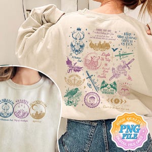 May include: A beige sweatshirt with a colorful graphic print featuring a wolf, a crow, a sword, and other symbols. The text on the graphic includes "Light It Up", "Whatever End", "City of Starlight", "There You Are", "Fire Breathing Bitch Queen", and "Don't Let The Hard Days Win".