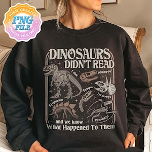 May include: Black sweatshirt with a graphic design featuring dinosaur skeletons and the text "DINOSAURS DIDN'T READ and we know What Happened To Them." The design includes illustrations of T-Rex, Velociraptor, Triceratops, and other dinosaurs.