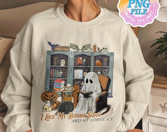 May include: A cream-coloured sweatshirt with a Halloween graphic. The graphic shows a ghost reading a book in a chair in front of a bookshelf. The text "I Like My Books Spicy and My Coffee Icy" is printed below the graphic.