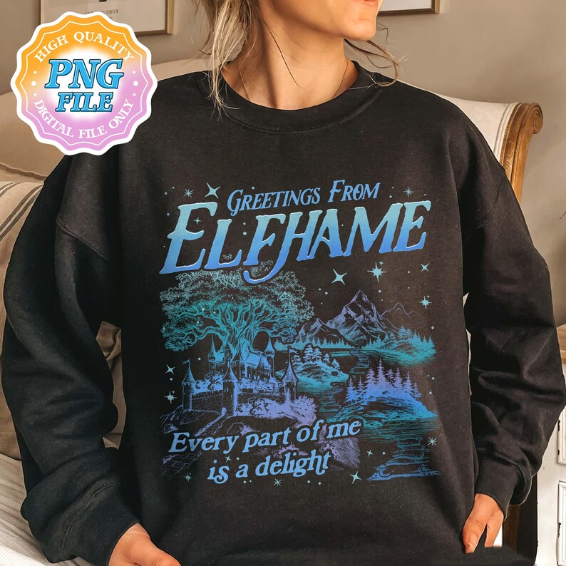 K&ouml;nnte beinhalten: Schwarzer Pullover mit einem blauen und wei&szlig;en Grafikdruck einer Fantasielandschaft mit einem Baum, Bergen und einem Schloss. Der Text "Greetings from Elfhame" und "Every part of me is a delight" ist auf dem Shirt gedruckt.