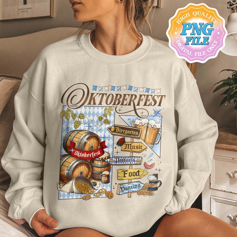 May include: Cream-colored sweatshirt with a colorful Oktoberfest graphic. The design includes wooden barrels, beer steins, pretzels, and directional signs pointing to Biergarten, Music, Food, and Dancing. The text "Oktoberfest" is prominently displayed.
