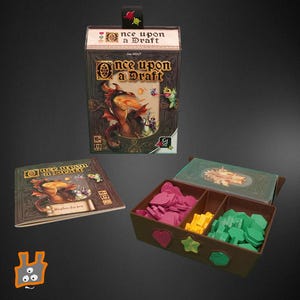 Peut inclure: Un jeu de société intitulé "Once Upon a Draft" avec une illustration de dragon. L'ensemble comprend une boîte de jeu, un livret de règles et un organisateur en bois avec des pièces de jeu roses, jaunes et vertes. La boîte a un ruban attaché.