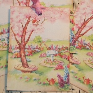 May include: Four vintage gift tags with a watercolor illustration of a pink flowering tree, a birdhouse, and a garden with flowers and a bird bath. The tags are tied with pink ribbon.
