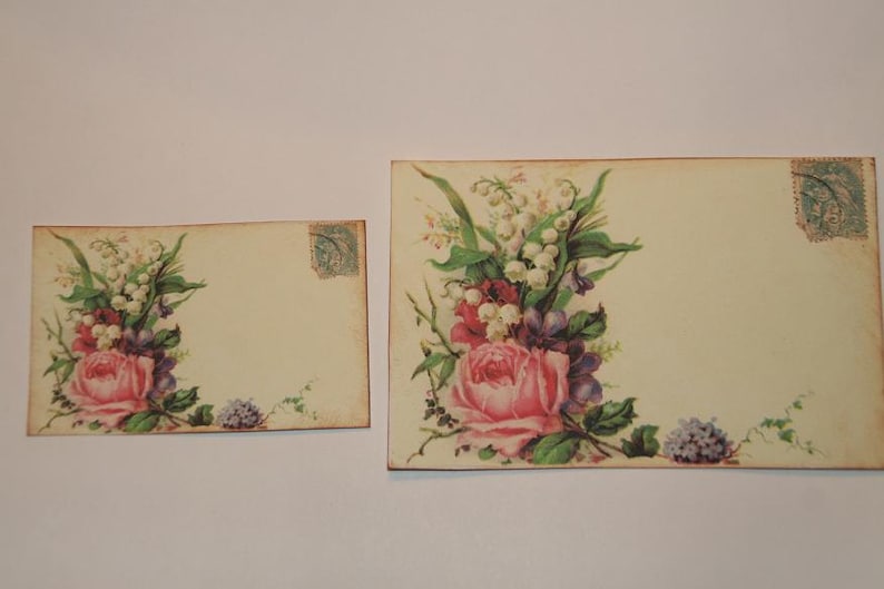May include: Two vintage style blank cards with a floral design. The larger card features a bouquet of pink roses, white lilies of the valley, and purple flowers. The smaller card has a similar floral design with a pink rose and white lilies of the valley.