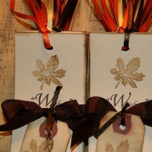 May include: Two brown and white bookmarks with a leaf design and the word "Wish" printed on them. Each bookmark is tied with a brown ribbon.