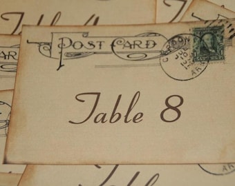 May include: A vintage-style postcard with a brown border and the text "Post Card" printed on it. The postcard has a faded green stamp with a portrait of a person. The text "Table 8" is printed in brown on the postcard.