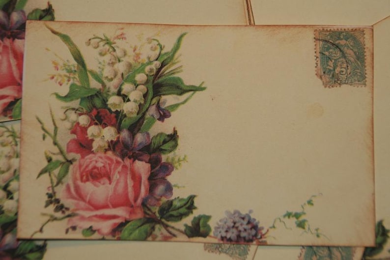 May include: A vintage postcard with a floral design featuring pink roses, white lilies of the valley, and purple flowers. The postcard has a blank space for writing a message and a vintage postage stamp in the upper right corner.