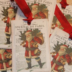 Pu&ograve; includere: Etichette regalo vintage di Natale con un Babbo Natale dei cartoni animati che porta un sacco di regali e un albero di Natale. Le etichette sono stampate con il testo "Journal de Paris" e il numero "117".