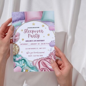 Pu&ograve; includere: Un invito a una festa in pigiama rosa e blu con un bordo circolare dorato. L'invito presenta illustrazioni di cuscini, una maschera per dormire, popcorn e un bicchiere d'acqua. Il testo sull'invito recita: "Unisciti a noi per una festa in pigiama, il 6&deg; compleanno di Adeline, sabato 20 gennaio alle 18:00, 123 Anywhere St., Any City, Indossa il tuo pigiama preferito! RSVP: -123-456-7890".