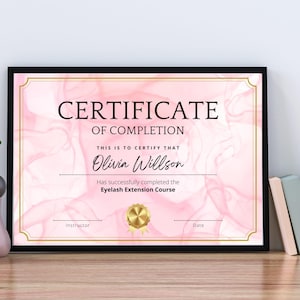 May include: A pink and gold certificate of completion for an Eyelash Extension Course. The certificate is framed in black and has the text "CERTIFICATE OF COMPLETION" at the top. The name "Olivia Willson" is printed in black cursive font. The text "Has successfully completed the Eyelash Extension Course" is printed below the name.