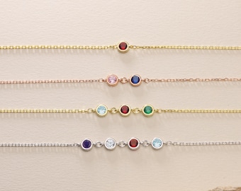 May include: Four delicate gold chain bracelets with colorful gemstone accents. The bracelets feature a single red gemstone, two gemstones, three gemstones, and five gemstones.