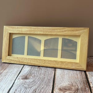 Peut inclure: Un cadre photo rectangulaire en bois clair avec quatre ouvertures arquées. Le cadre a une finition naturelle. Les ouvertures ont un fond jaune clair et sont conçues pour contenir des photographies.