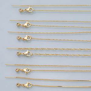 May include: A set of eight gold chain extenders with a variety of chain styles, including cable, rope, and box chains. Each extender features a lobster clasp and a small bead at the end.