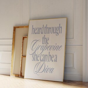 Op de afbeelding: Een wit ingelijst canvasprint met de tekst "heard through the grapevine she can be a Diva" in een lichtpaarse lettertype.