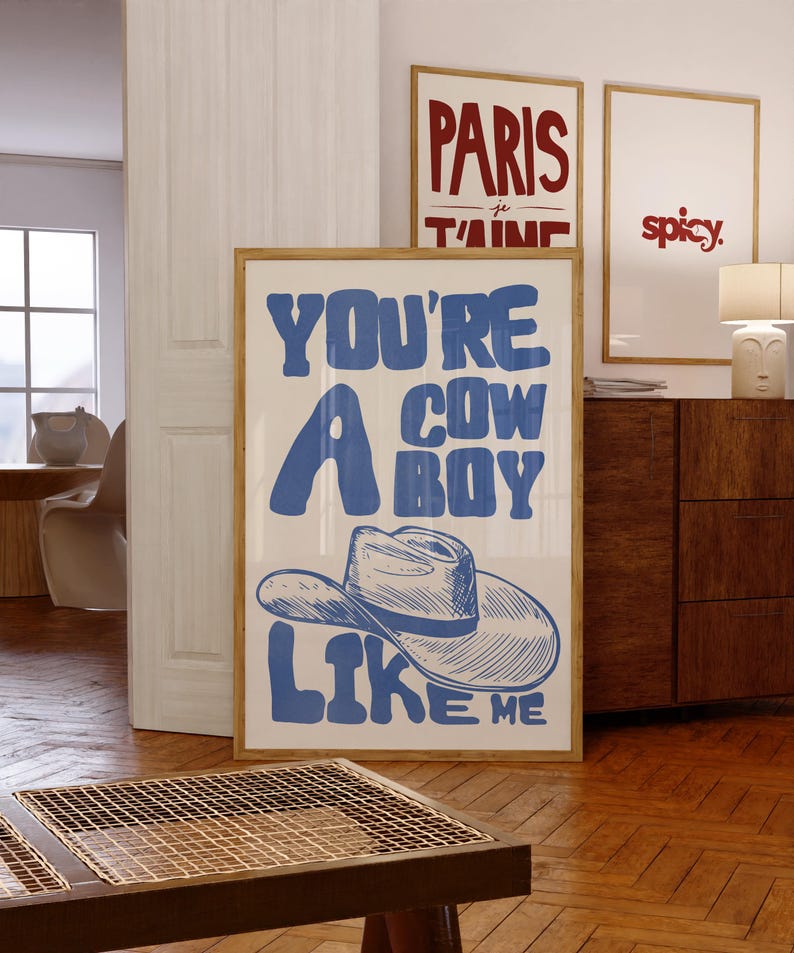 Puede incluir: Una impresi&oacute;n art&iacute;stica enmarcada con el texto "YOU'RE A COWBOY LIKE ME" en azul, con una ilustraci&oacute;n de sombrero de vaquero. Se ven otras dos impresiones enmarcadas, una con "PARIS je t'aime" y otra con la palabra "spicy."
