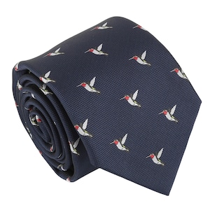 Könnte beinhalten: Eine dunkelmarineblaue Krawatte mit einem sich wiederholenden Muster aus kleinen Kolibris. Jeder Kolibri ist mit einer leuchtend roten Kehle, einer weißen Brust und grünen Flügeln auf dem strukturierten Stoff der Krawatte dargestellt.