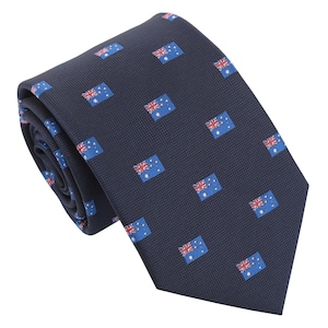 Può includere: Una cravatta blu navy con un motivo ripetuto della bandiera australiana. Le bandiere sono blu, rosse e bianche, su uno sfondo strutturato. La cravatta è arrotolata, mostrando la trama del tessuto.