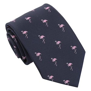 May include: A navy blue necktie featuring a repeating pattern of pink flamingo illustrations. The tie is made of a textured fabric and is folded over itself, showcasing the design. The flamingo design adds a touch of whimsy to the classic accessory.