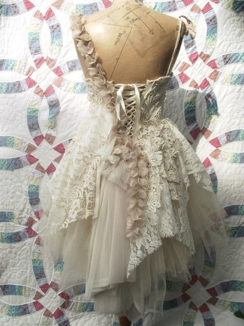 Puede incluir: Un vestido de novia de encaje blanco con una falda de tul y un corpi&ntilde;o de encaje. El vestido tiene una espalda de cors&eacute; con un lazo de cinta de sat&eacute;n. El vestido est&aacute; decorado con delicadas flores de encaje.