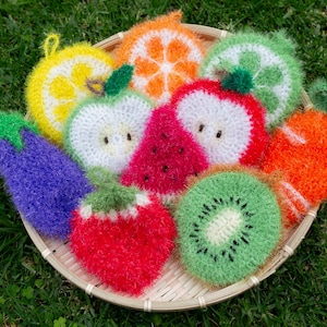 May include: A set of nine colorful crocheted fruit and vegetable shaped dishcloths in a woven basket. The dishcloths are shaped like a lemon, apple, watermelon, kiwi, orange, eggplant, and strawberry.