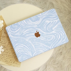 May include: A light blue laptop skin with a white swirl pattern. The Apple logo is visible on the skin.