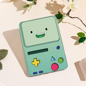 May include: A mint green phone case featuring a cartoon face with black eyes and a smiling mouth. The case has a yellow plus sign, a blue triangle, a green circle, and a pink circle. The case is a fun accessory.