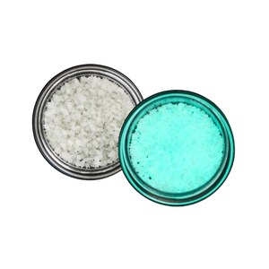 May include: Two small, round containers filled with coarse granules. One container holds white granules, while the other is filled with turquoise granules. The containers have silver rims and are set against a white background.