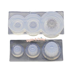 May include: Two clear silicone molds for crafting, each with three thimble-shaped cavities of varying sizes. The molds have a textured interior design. The brand name "Sophie & Toffee" is printed on the bottom mold.