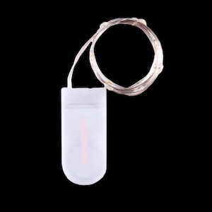 Peut inclure: Une guirlande de minuscules lumières LED sur un fin fil d'argent, reliée à un petit boîtier de piles blanc translucide. Les lumières sont espacées uniformément le long du fil. Le boîtier de piles a un composant interne rose. Le fond est noir.