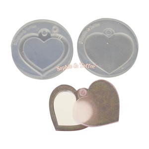 May include: Three heart-shaped molds and a small heart-shaped mirror. The molds are clear, circular, and have a heart shape within. The mirror is bronze-colored and has a hinged cover. The text "Sophie & Toffee" is visible on the molds.