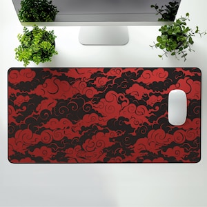 May include: A red and black mouse pad with a swirling cloud pattern. The mouse pad is on a white desk with a computer monitor and two potted plants.