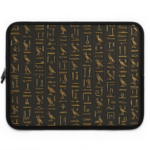 Puede incluir: Funda negra para portátil con un patrón de jeroglíficos dorados. El diseño incluye varios símbolos y figuras de aves, dispuestos en columnas verticales. La funda tiene una cremallera y un borde negros.