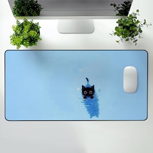 May include: A light blue desk mat with a black cat illustration in water. The cat has large, round eyes and is surrounded by ripples. A white mouse is on the right side of the mat. The mat is rectangular.