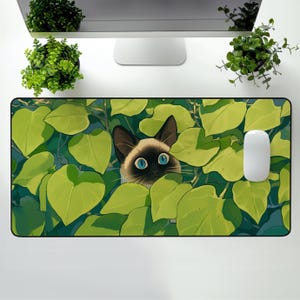 Puede incluir: Alfombrilla de rat&oacute;n rectangular con un gato siam&eacute;s mirando a trav&eacute;s de hojas verdes. El gato tiene ojos azules y una cara marr&oacute;n con orejas marrones oscuras. Un rat&oacute;n de ordenador blanco est&aacute; a la derecha. El fondo es azul claro.