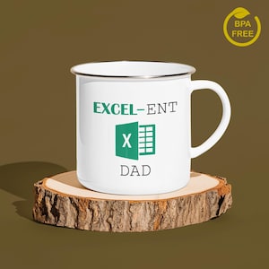 May include: White enamel mug with a green Excel logo and the text "EXCEL-ENT DAD". The mug is sitting on a wooden coaster.