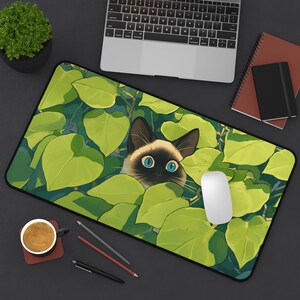 Alfombrilla de ratón con diseño de gato siamés: Gato de ojos azules escondido entre plantas. 12" × 22"