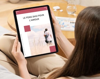 May include: A digital tablet displaying a guide titled "Le Feng Shui Pour L'Amour" with a couple standing in a field of tall grass. The tablet is being held by a person.