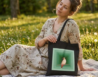 May include: Black tote bag featuring a bird illustration within a green square design. The bird is perched on a branch, with a cream-colored body and a red crest. The bag has long black handles.