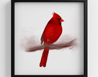 May include: A square framed wall art piece featuring a vibrant red cardinal bird perched on a thin, wispy brown branch. The bird has a pointed crest, a black mask around its eyes, and a bright orange beak, set against a plain white background.