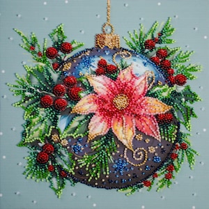 Puede incluir: Un adorno navideño con cuentas con una flor de pascua y bayas rojas. El adorno es azul oscuro con detalles dorados y está rodeado de agujas de pino verdes. El fondo es azul claro con puntos blancos.