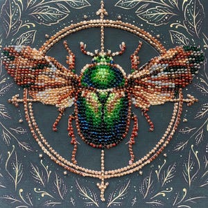 May include: A beaded insect art piece. The central focus is a detailed beetle, primarily green and blue, with wings in shades of brown, gold, and white. The beetle is surrounded by a gold beaded circle and a dark background with gold leaf accents.