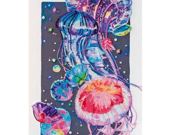 Könnte beinhalten: Ein perlenbesetztes Wandbild mit drei Quallen in Rosa-, Lila- und Blautönen. Die Quallen bestehen aus kleinen, reflektierenden Perlen auf einem dunkelgrauen rechteckigen Hintergrund, mit langen, fließenden Tentakeln und kreisförmigen Akzenten.